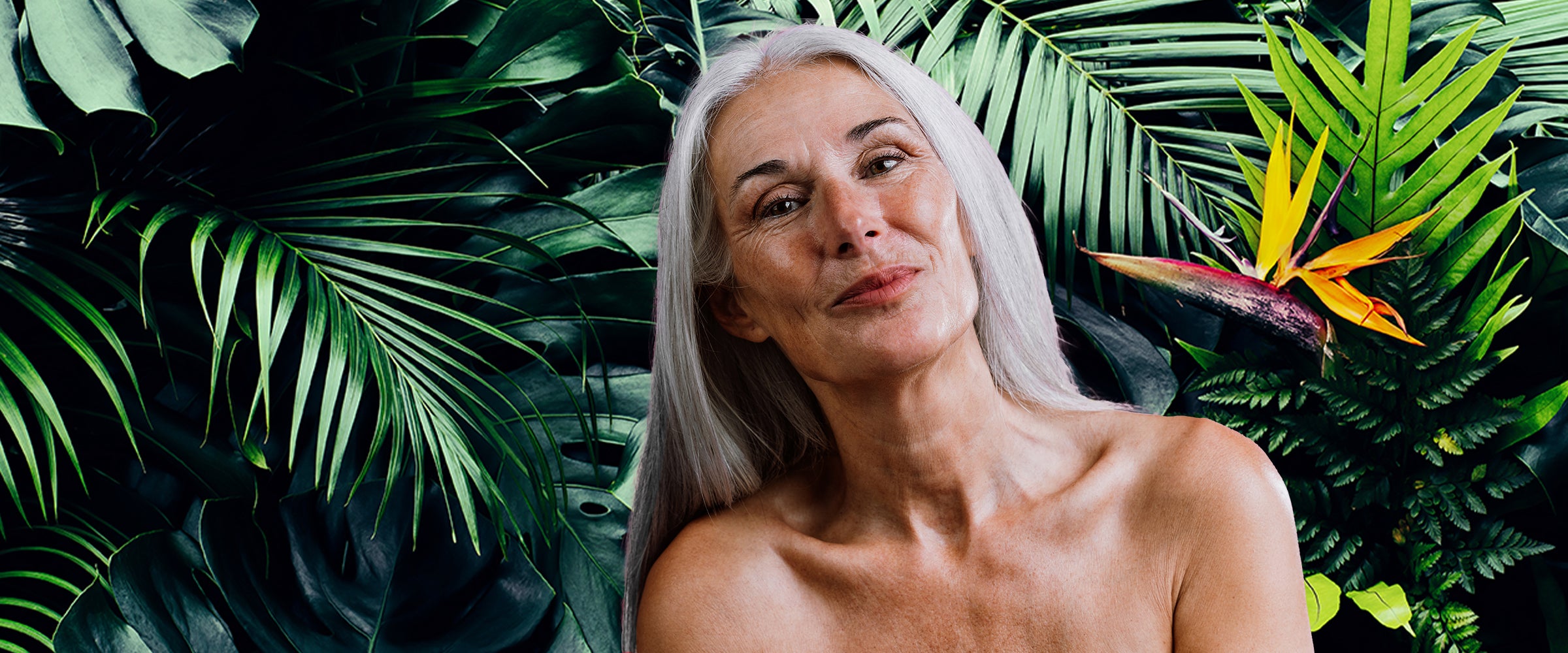 Mature woman with gray hair standing among tropical plants represents anti-aging benefits of Jamaican Black Castor Oil 