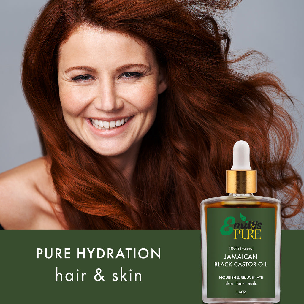 Mature woman with flowing red hair with bottle of Emily's Pure Jamaican Black Castor Oil for hydration of hair and skin.