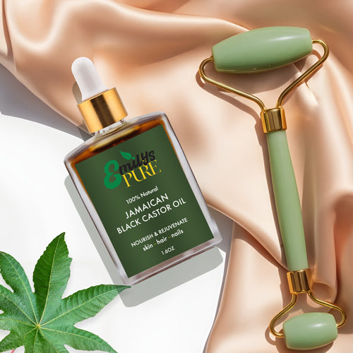 Emily's Pure Jamaican Black Castor Oil bottle 1.6oz with a jade roller on a beige fabric background for skin care.